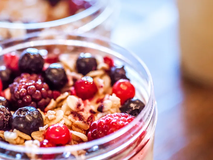 A yoghurt and granola pot topped with berries.