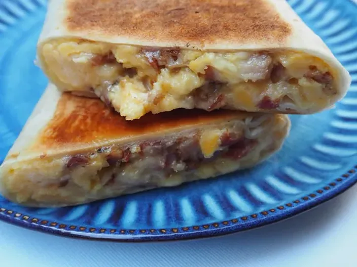 A breakfast toastie cut open, filled with bacon and egg.