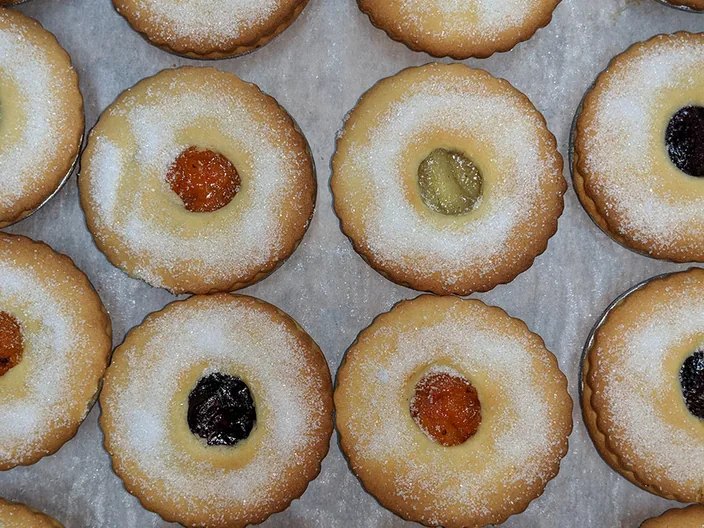 A tray of sugar dusted fruit tarts with jam centres.