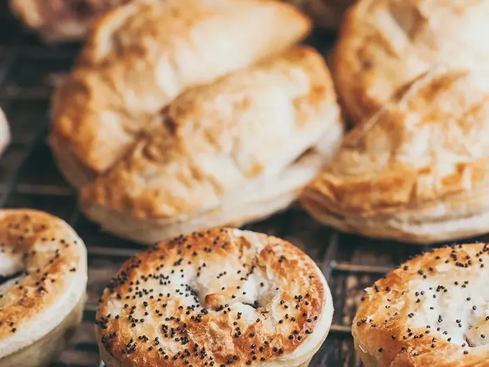 Golden pastries and rolls on a bakery rack.