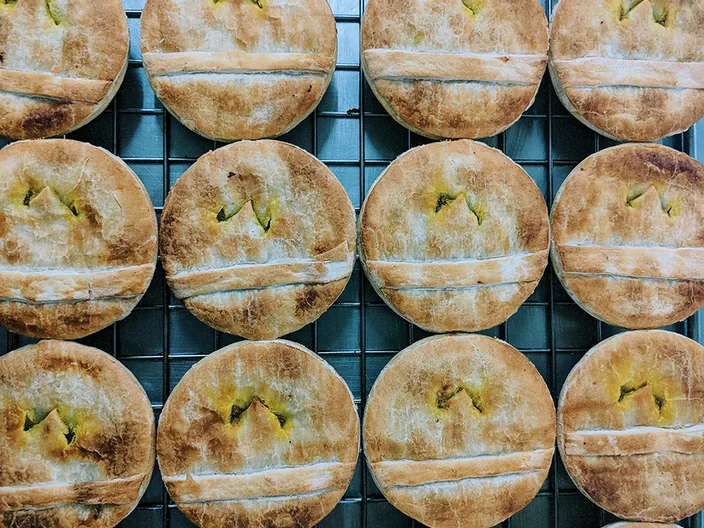 A tray of golden round pies cooling on a wire rack.