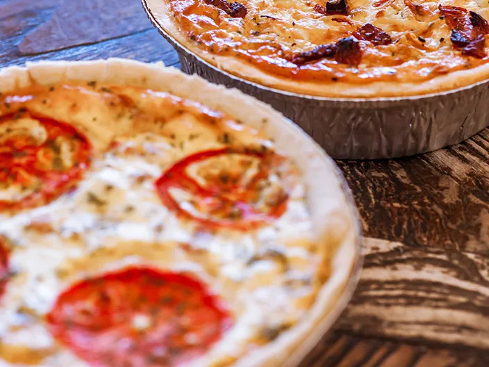 Two tomato topped family quiches.